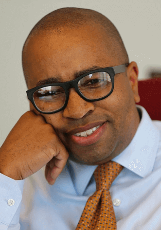 bismarck-myrick-owner-of-alexandria-legal Bismarck Myrick an Estate Planner for young families and owner of Alexandria Legal wearing a blue shirt and orange tie.